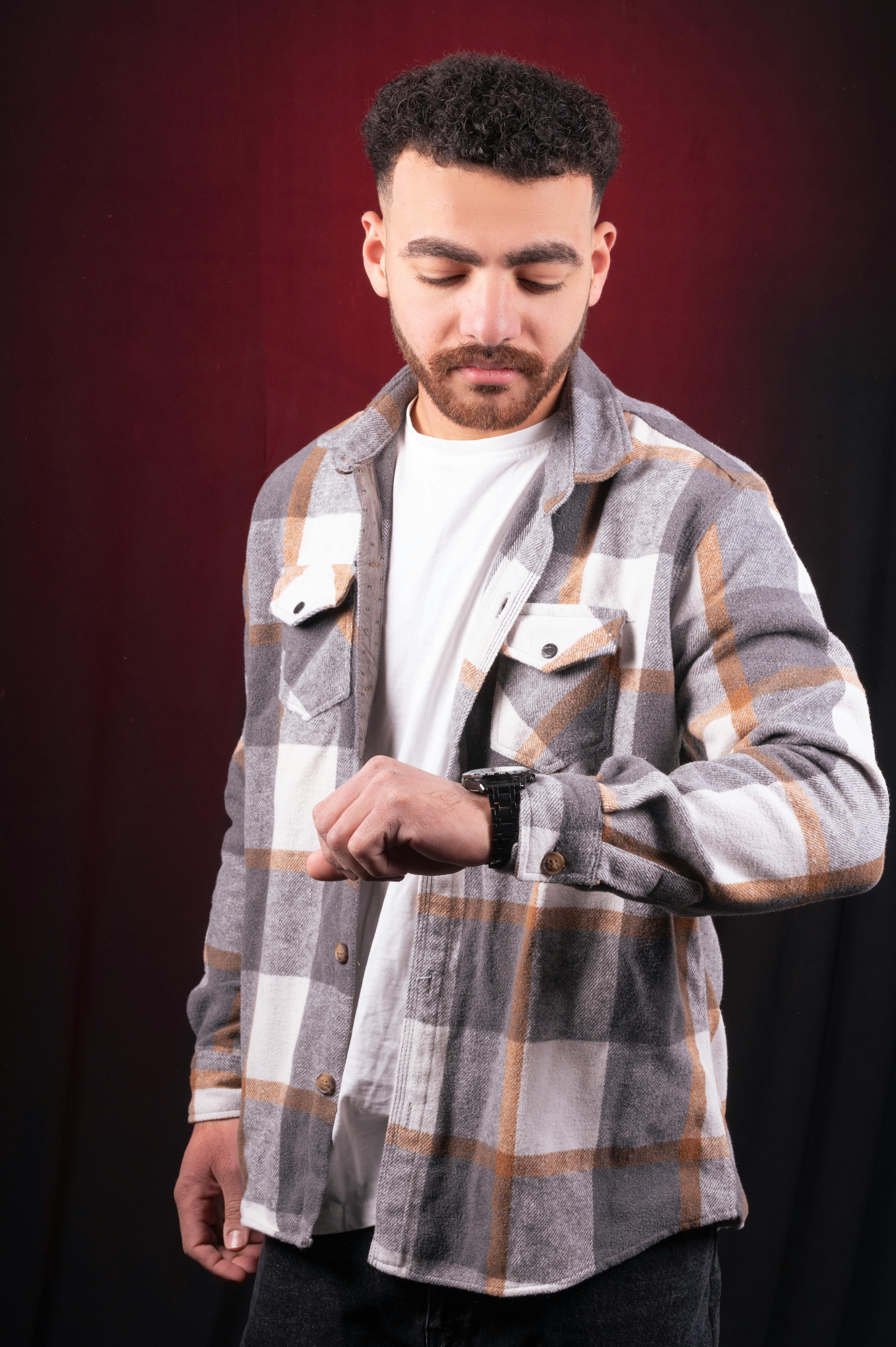 Miễn phí Người đàn ông giản dị mặc áo sơ mi kẻ caro nhìn đồng hồ trên nền đỏ, ý niệm về sự đúng giờ. Ảnh lưu trữ