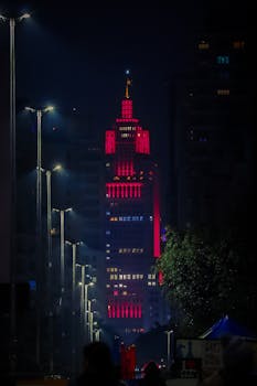 Vibrant skyscraper illuminated by colorful lights against a city night backdrop, showcasing modern architecture.