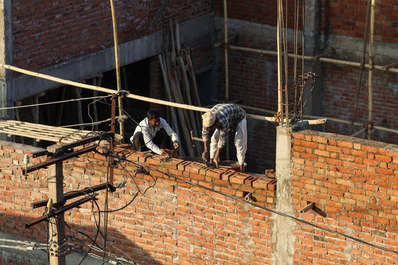 Masons laying a brick wall on a multi-storey building site Masons laying a brick wall on a multi-storey building site
