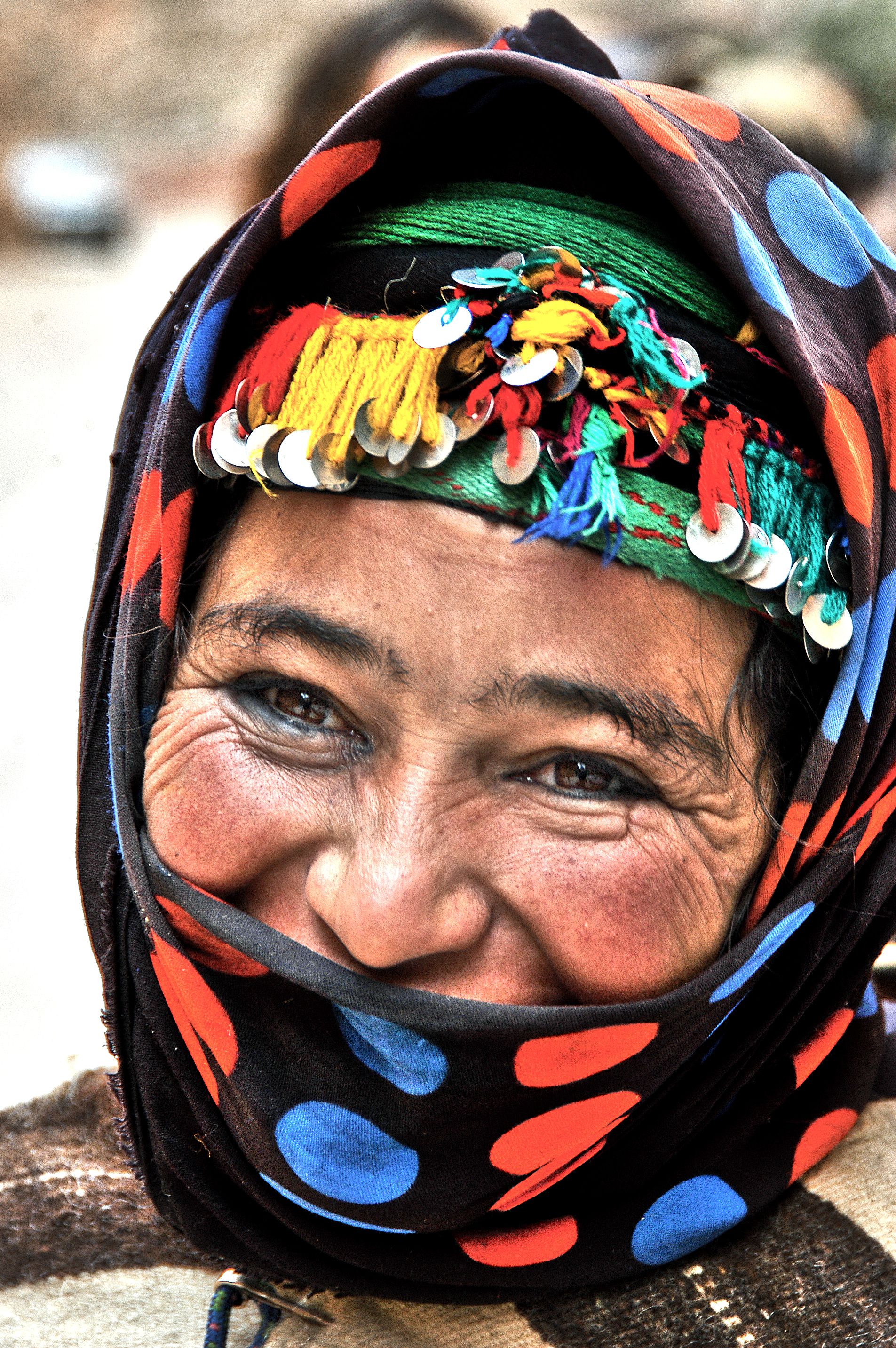 Close-up of Berber woman in traditional attire smiling in Tinghir, Morocco.