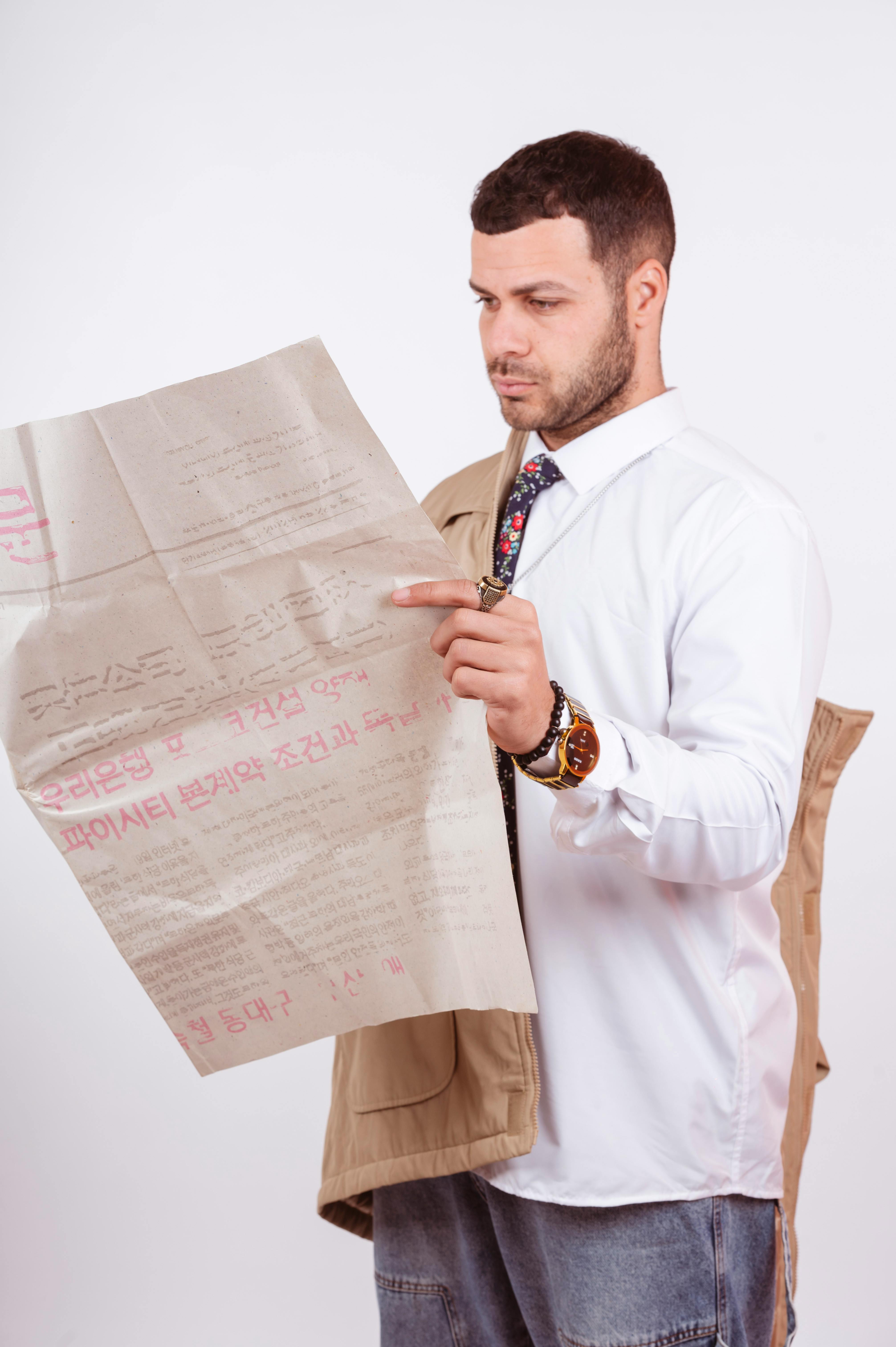 Δωρεάν Ενήλικο αρσενικό με επίσημη ενδυμασία που διαβάζει προσεκτικά ένα έγγραφο. Εσωτερική ρύθμιση με ουδέτερο φόντο. Φωτογραφία από στοκ φωτογραφιών