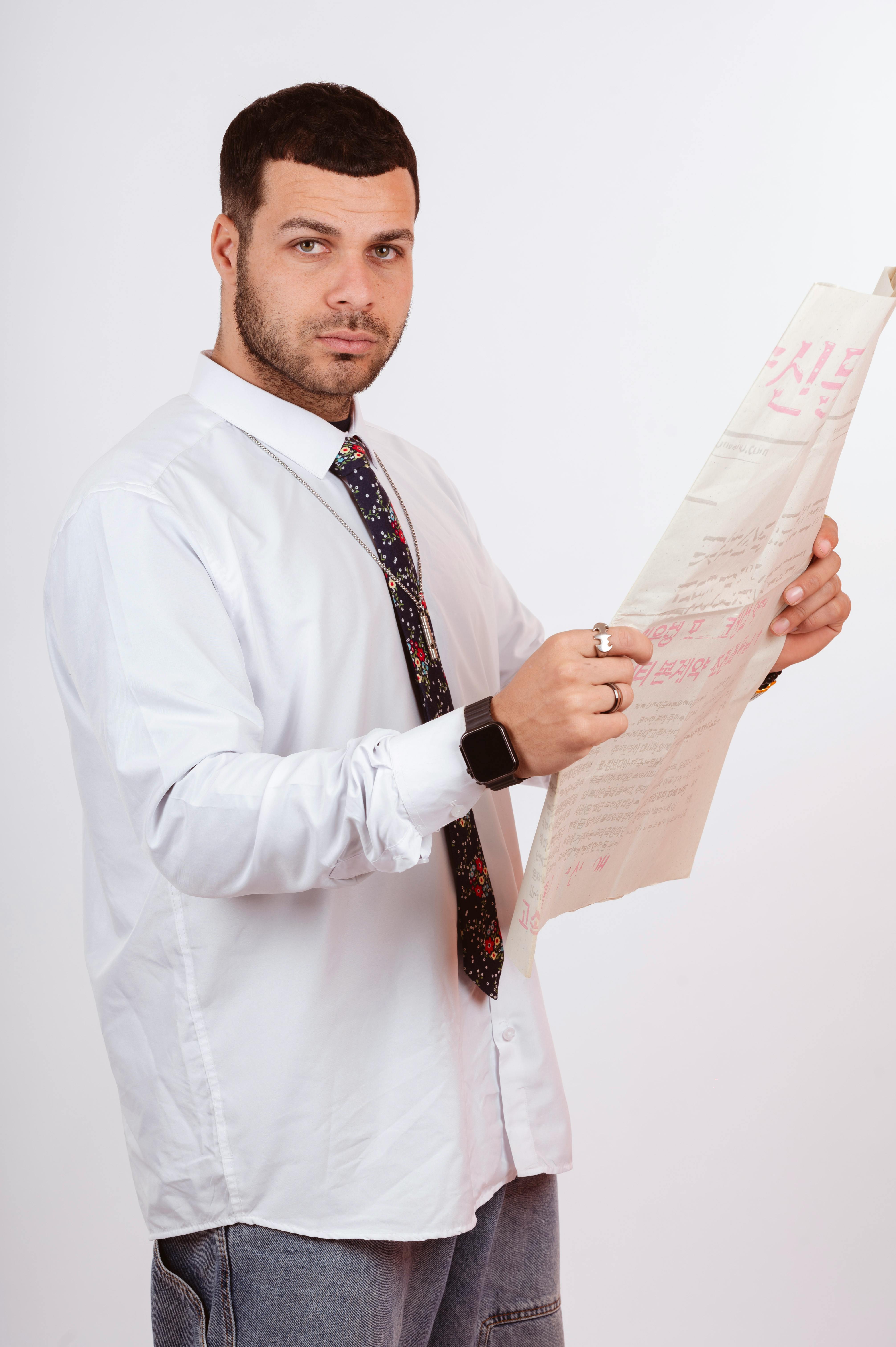 Gratis En forretningsmann i uformelt antrekk leser en avis i et studio, og formidler profesjonelt fokus. Arkivbilde