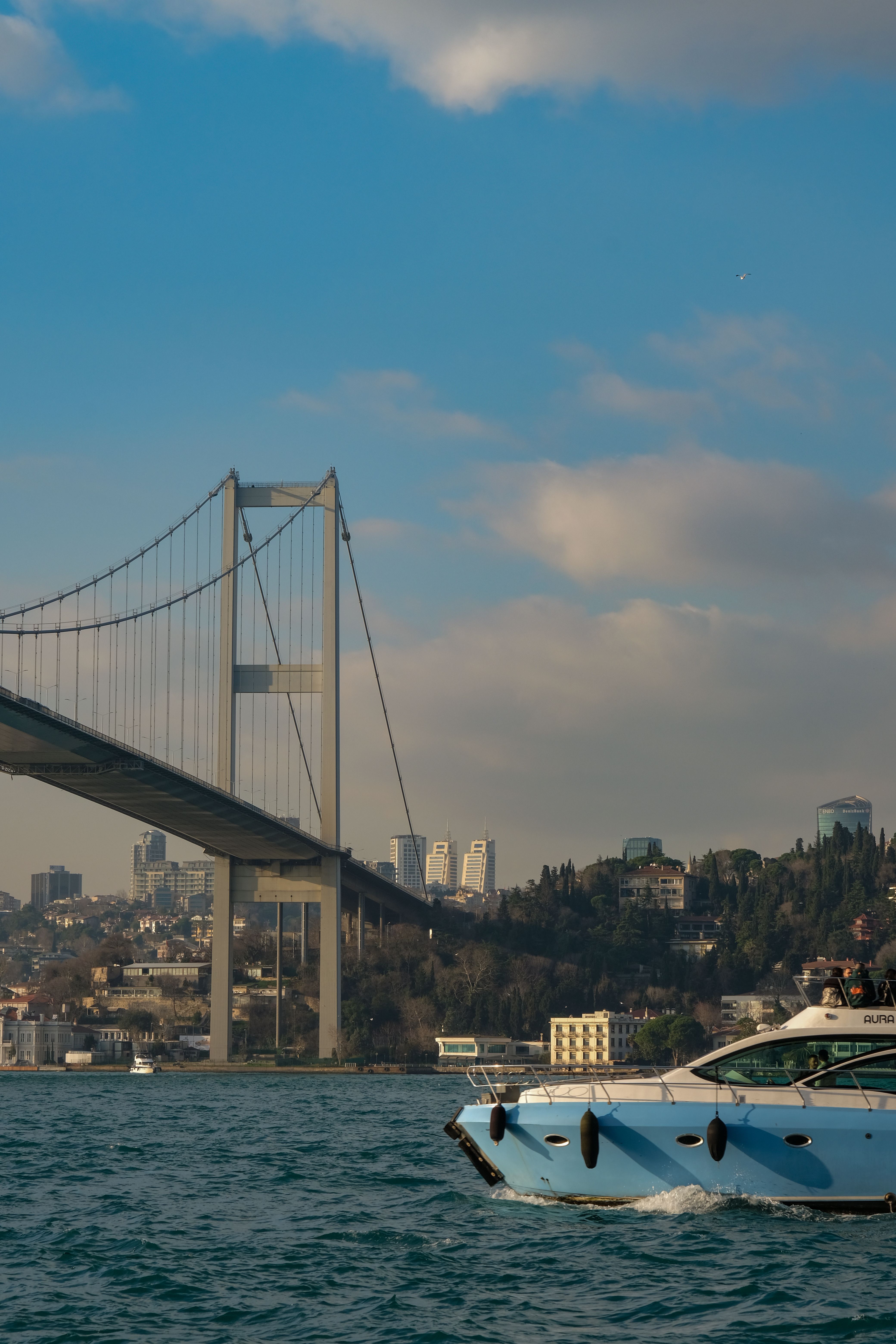 Free A vibrant scene of a yacht cruising near the Bosphorus Bridge with İstanbul skyline in the background. Stock Photo