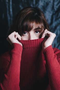 一位身穿红色毛衣的女子在室内摆姿势，目光迷人，特写肖像