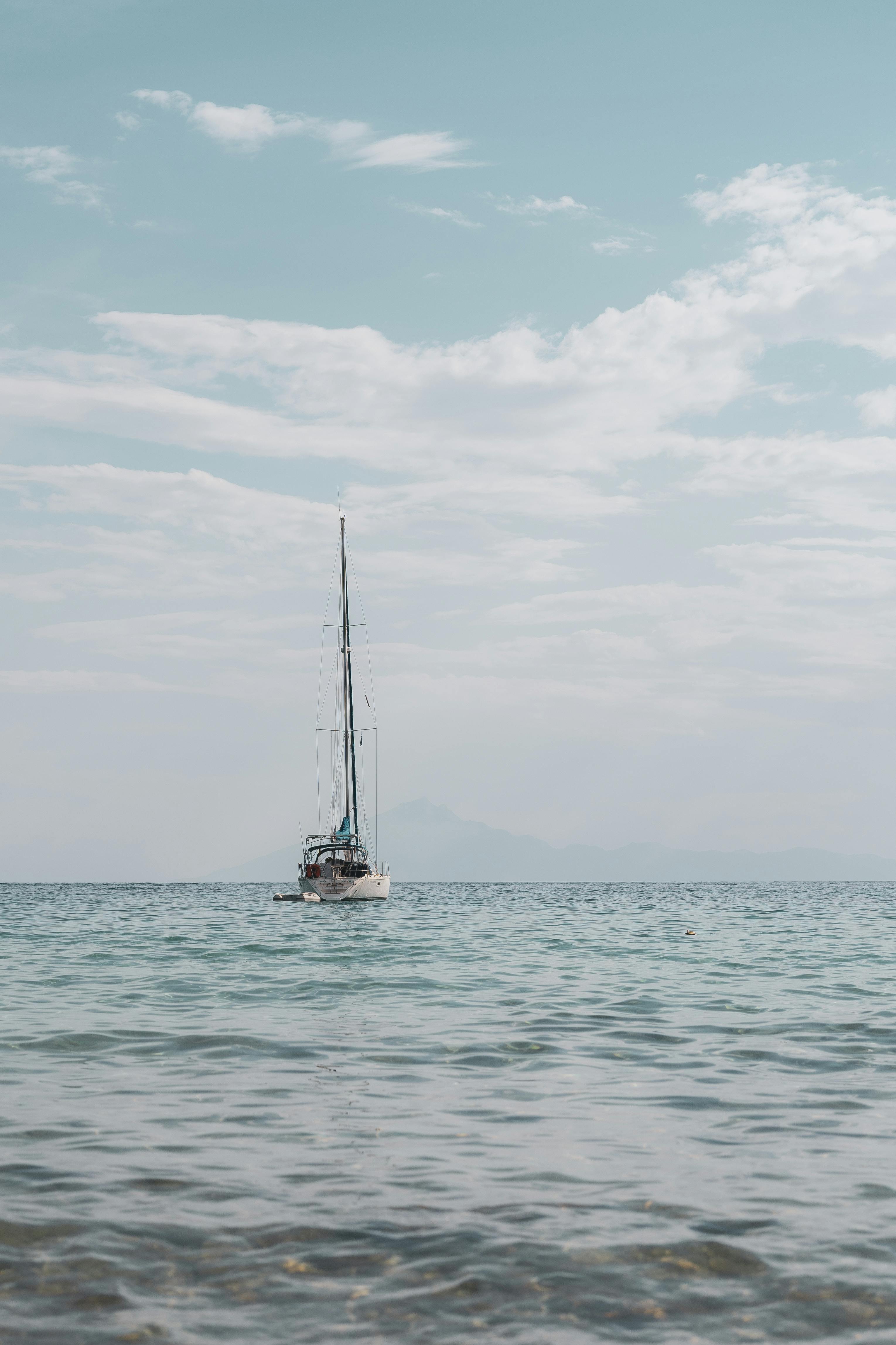 A peaceful sailboat drifts on the calm ocean under a clear sky, capturing serenity and freedom.