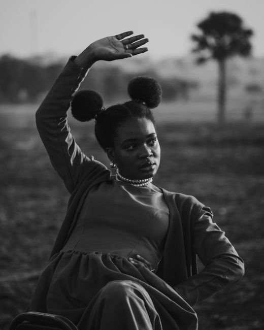 Striking black and white portrait of a woman posing elegantly in an outdoor setting.