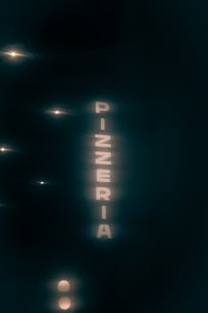 A bold neon sign for a pizzeria glowing at night, creating a vibrant street scene.