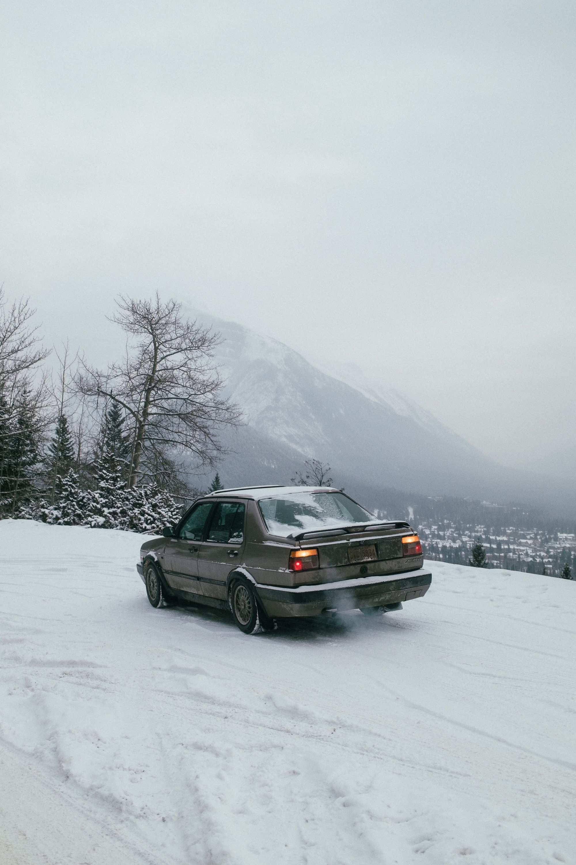 Auto auf verschneiter Bergstraße vor alpinem Panorama