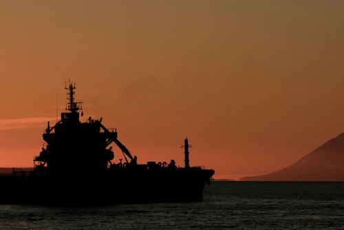 Free A silhouette of a ship against a dramatic sunset in Iceland with distant mountains. Stock Photo