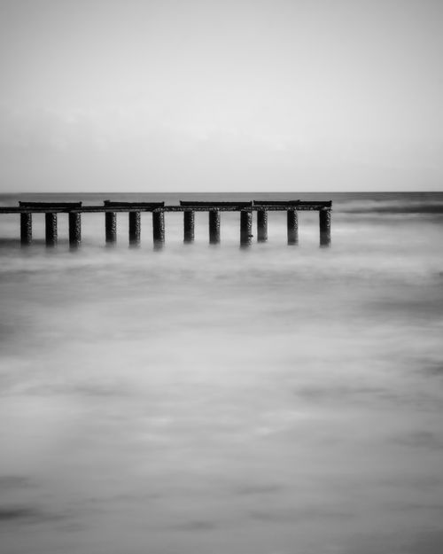 Free Black and white long exposure of a solitary pier over calm sea. Stock Photo