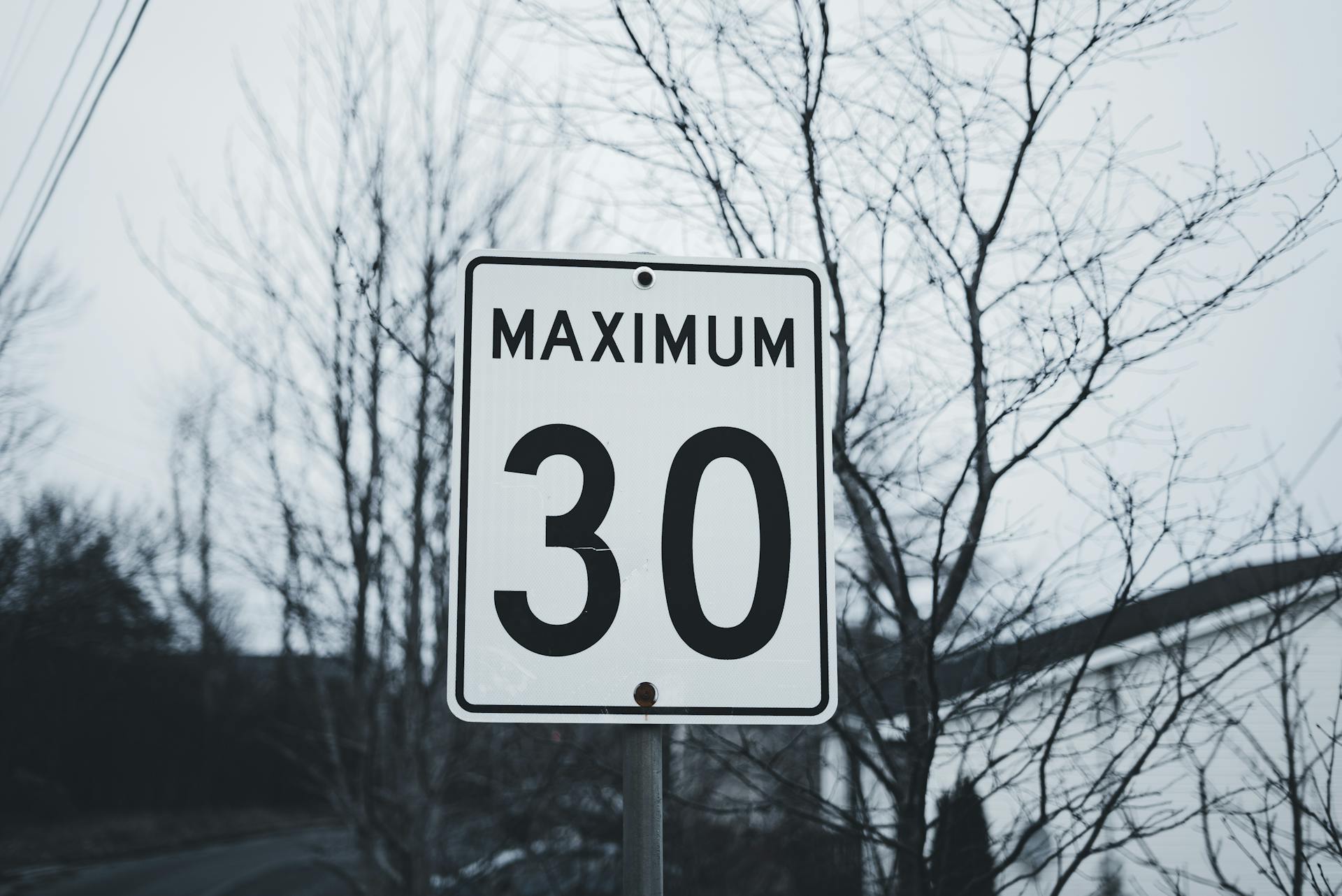 Photograph of a road sign indicating a maximum speed limit of 30 in a winter setting.