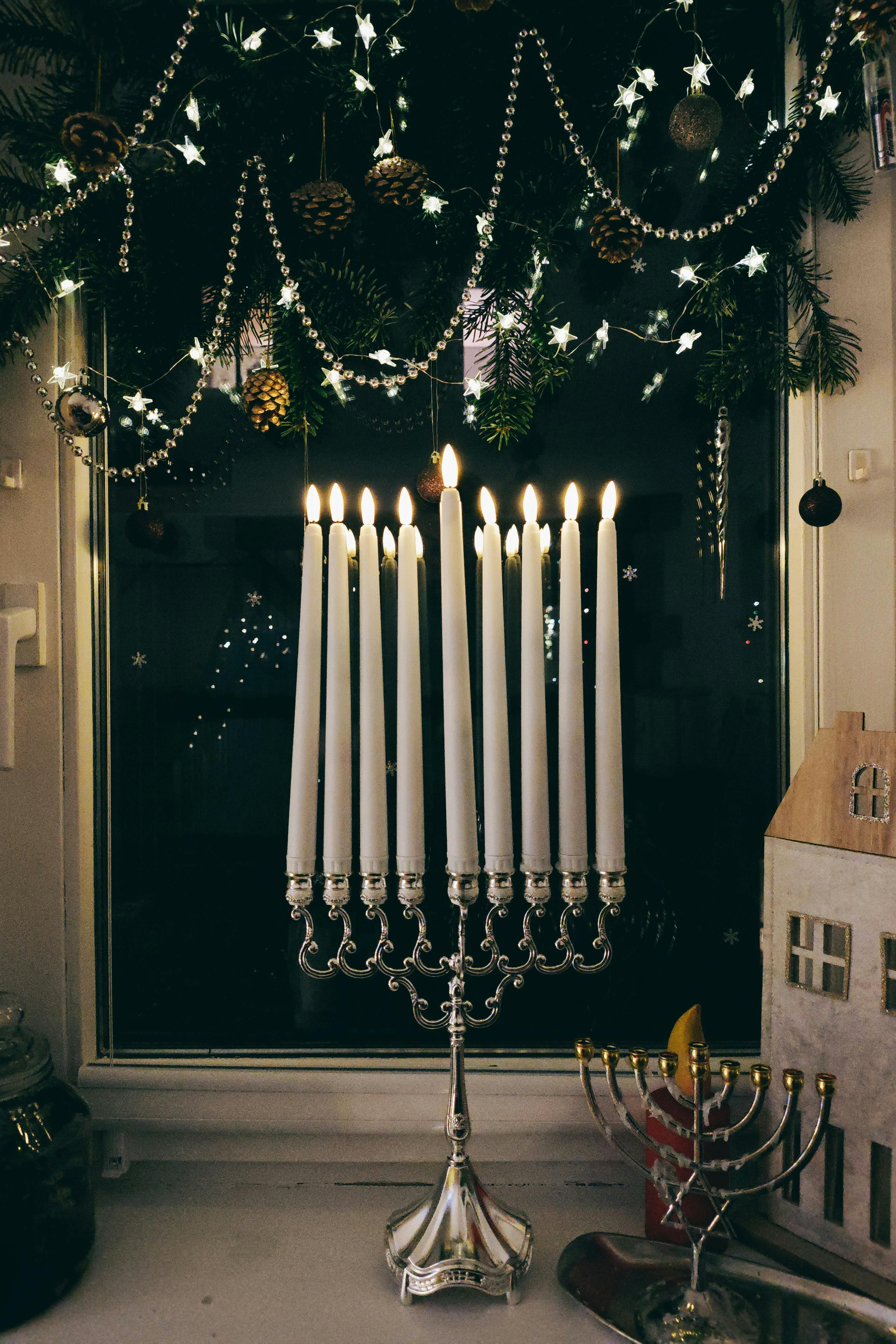 Menorah with lit candles on a festive windowsill, celebrating Hanukkah.