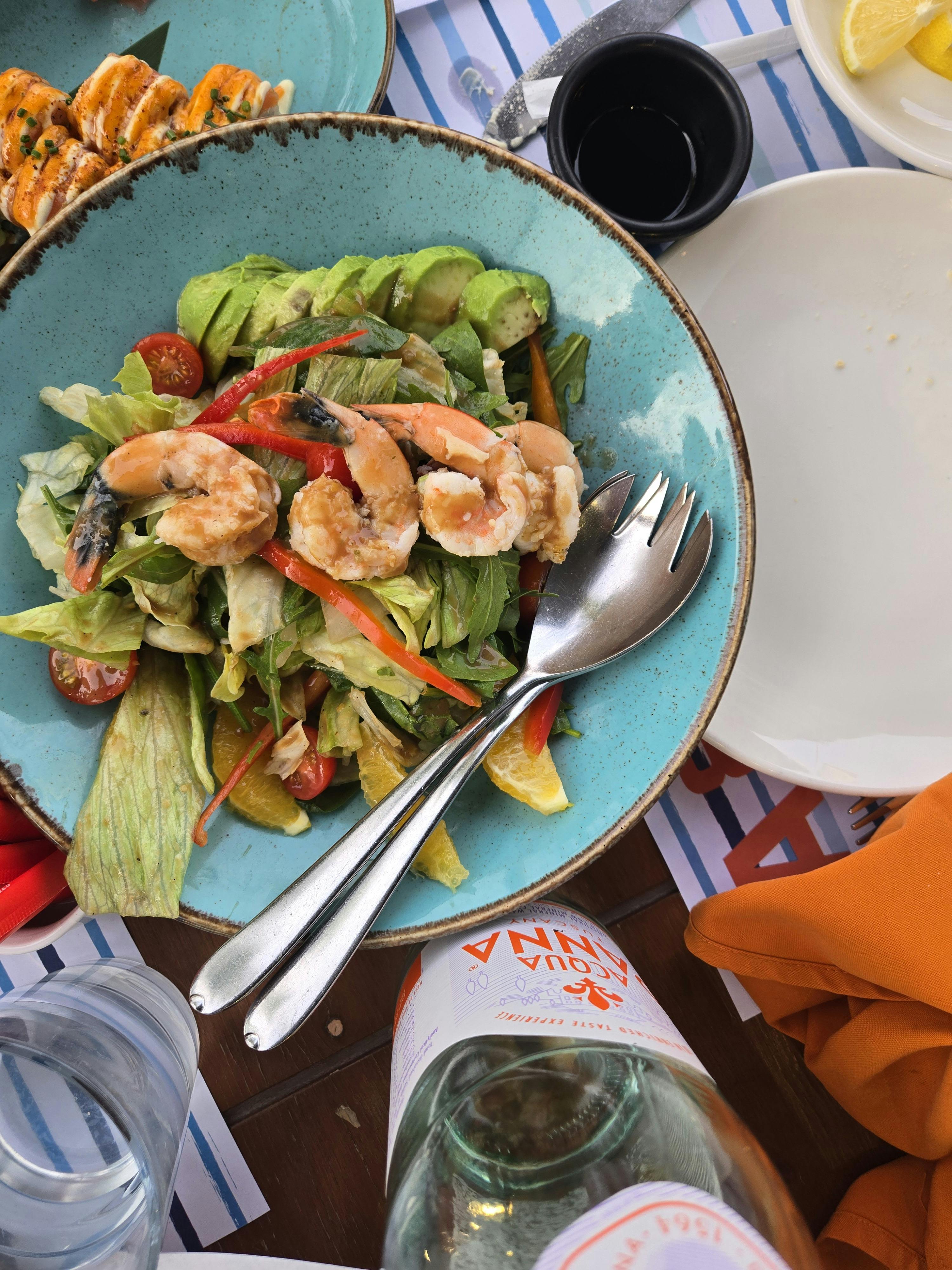 Kevin  Early - Vibrant shrimp salad with fresh vegetables in a blue bowl on a wooden table.