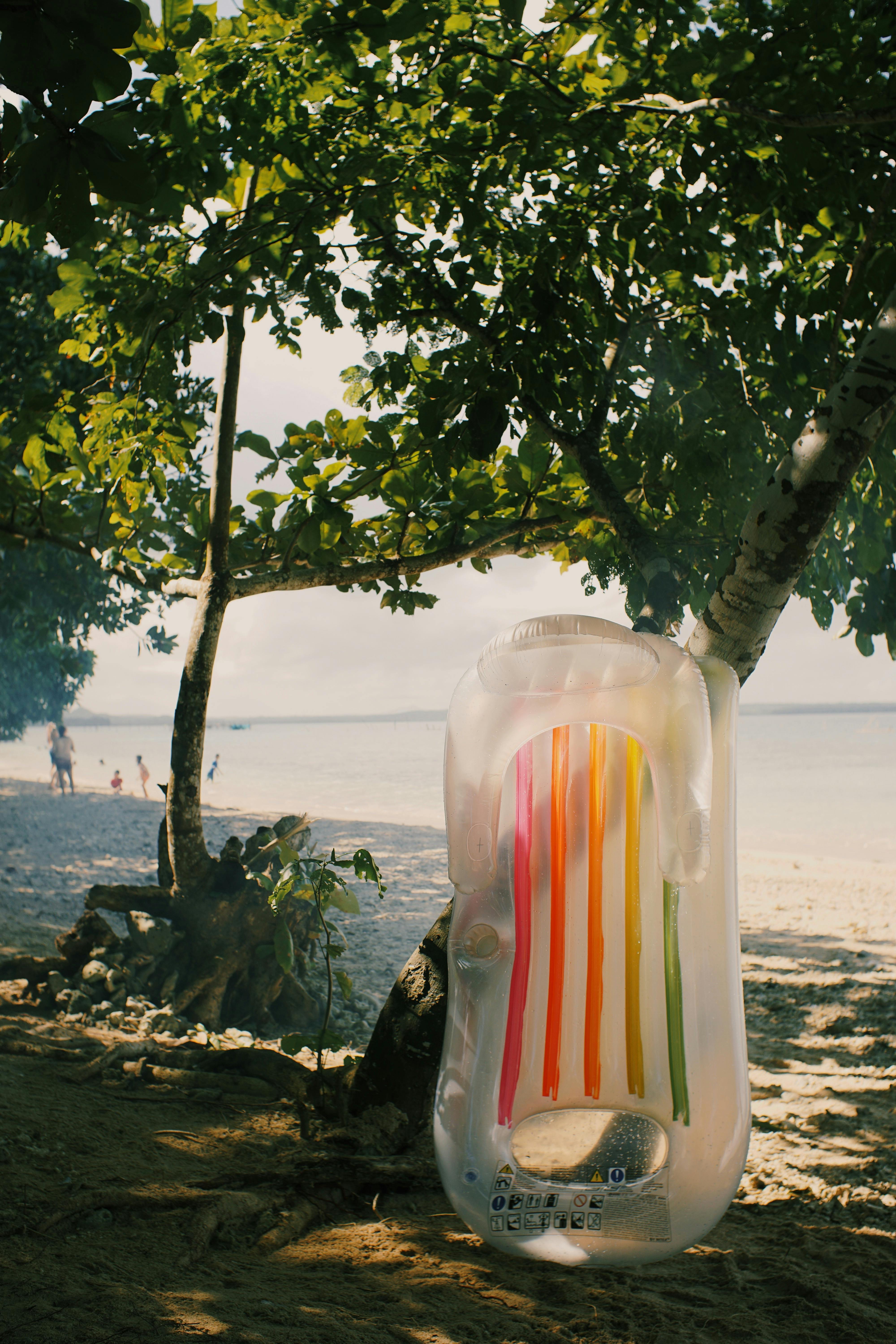 A vibrant inflatable hanging from a tree on a serene tropical beach.