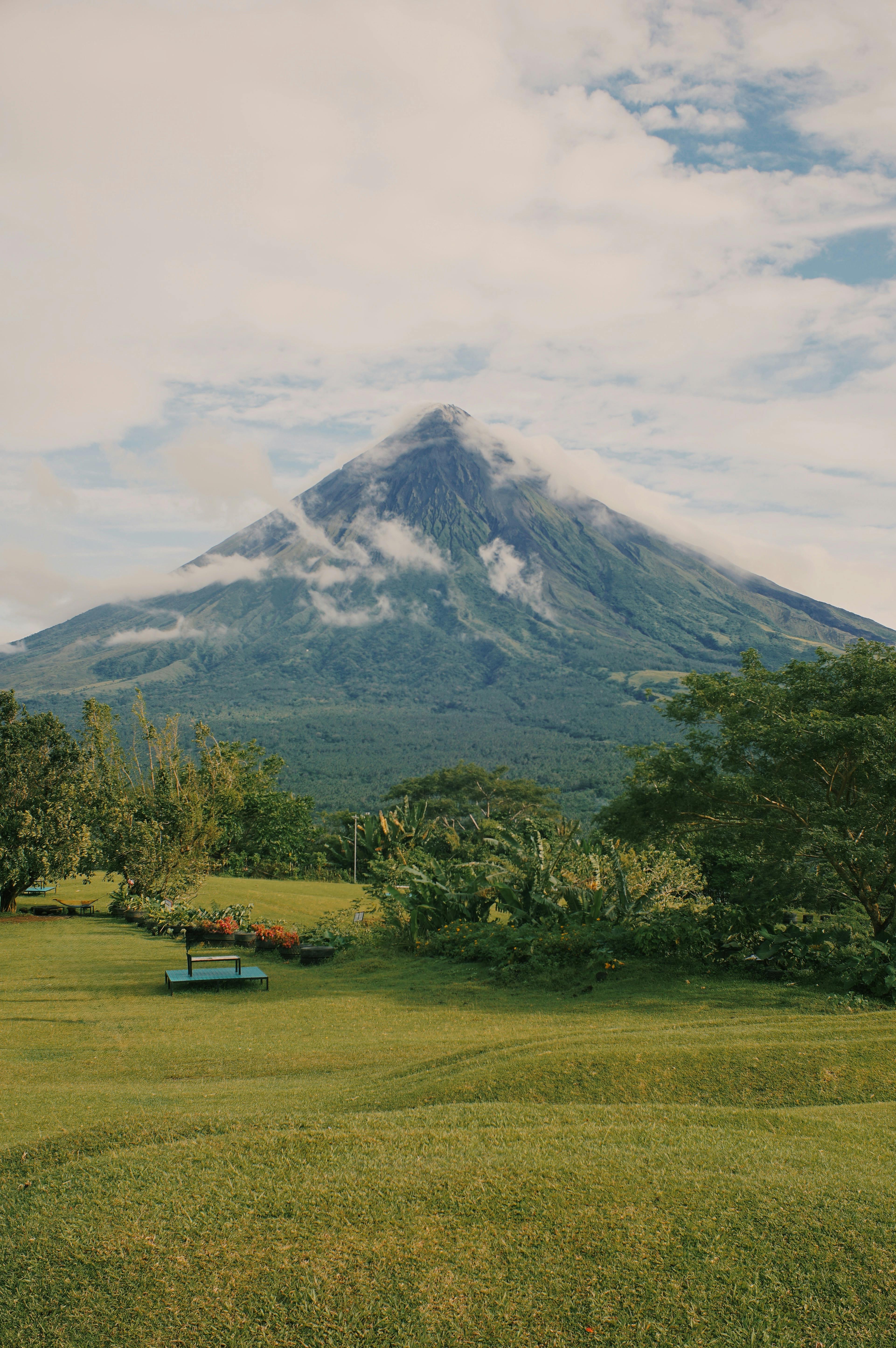 Scenic view of a majestic volcano surrounded by lush greenery and clear sky.