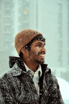 Outdoor portrait of a smiling man in a snowy Toronto winter, wearing a beanie and plaid jacket.