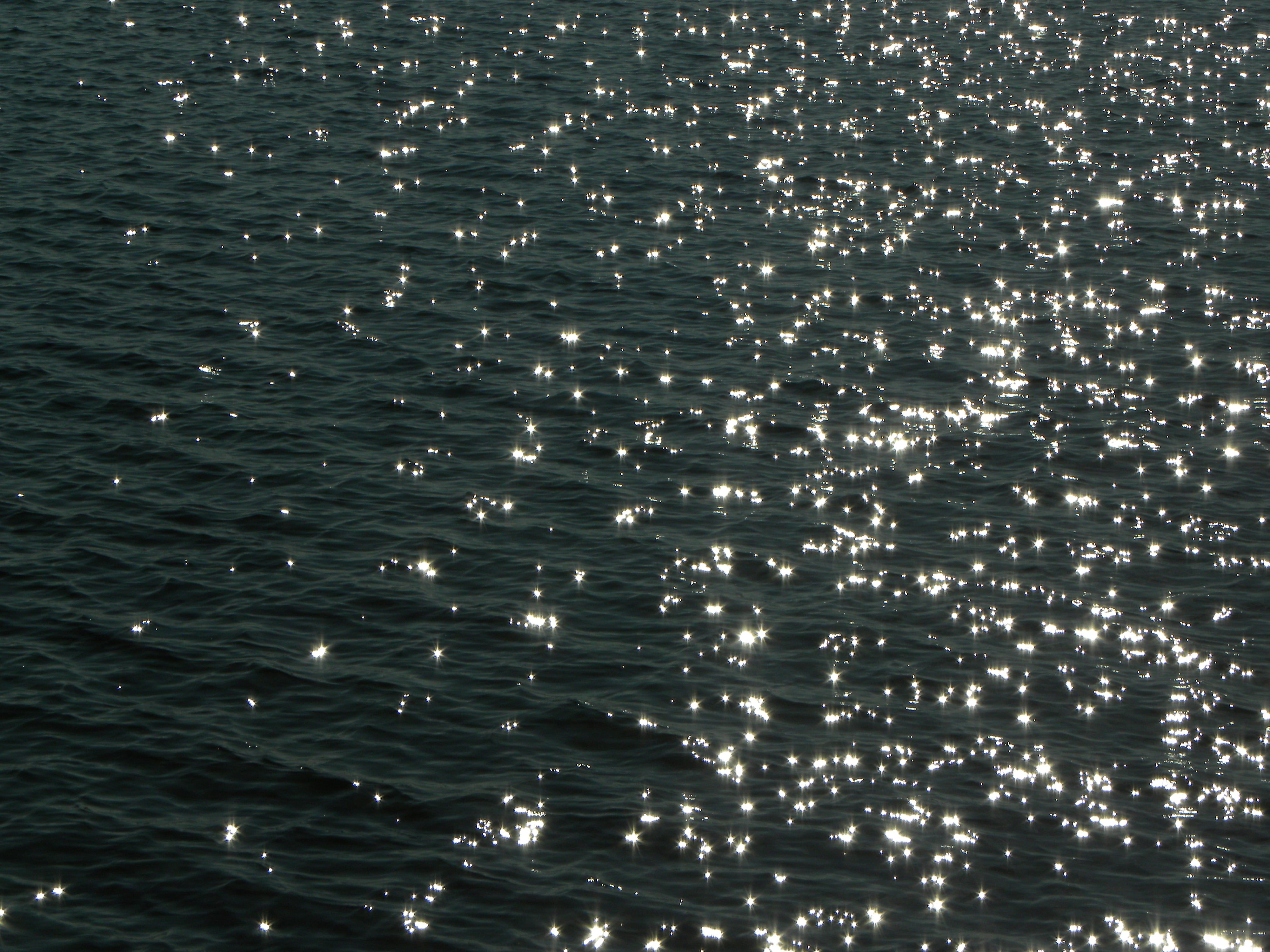 Bright sunlight reflecting on gentle ocean waves creating a sparkling effect.