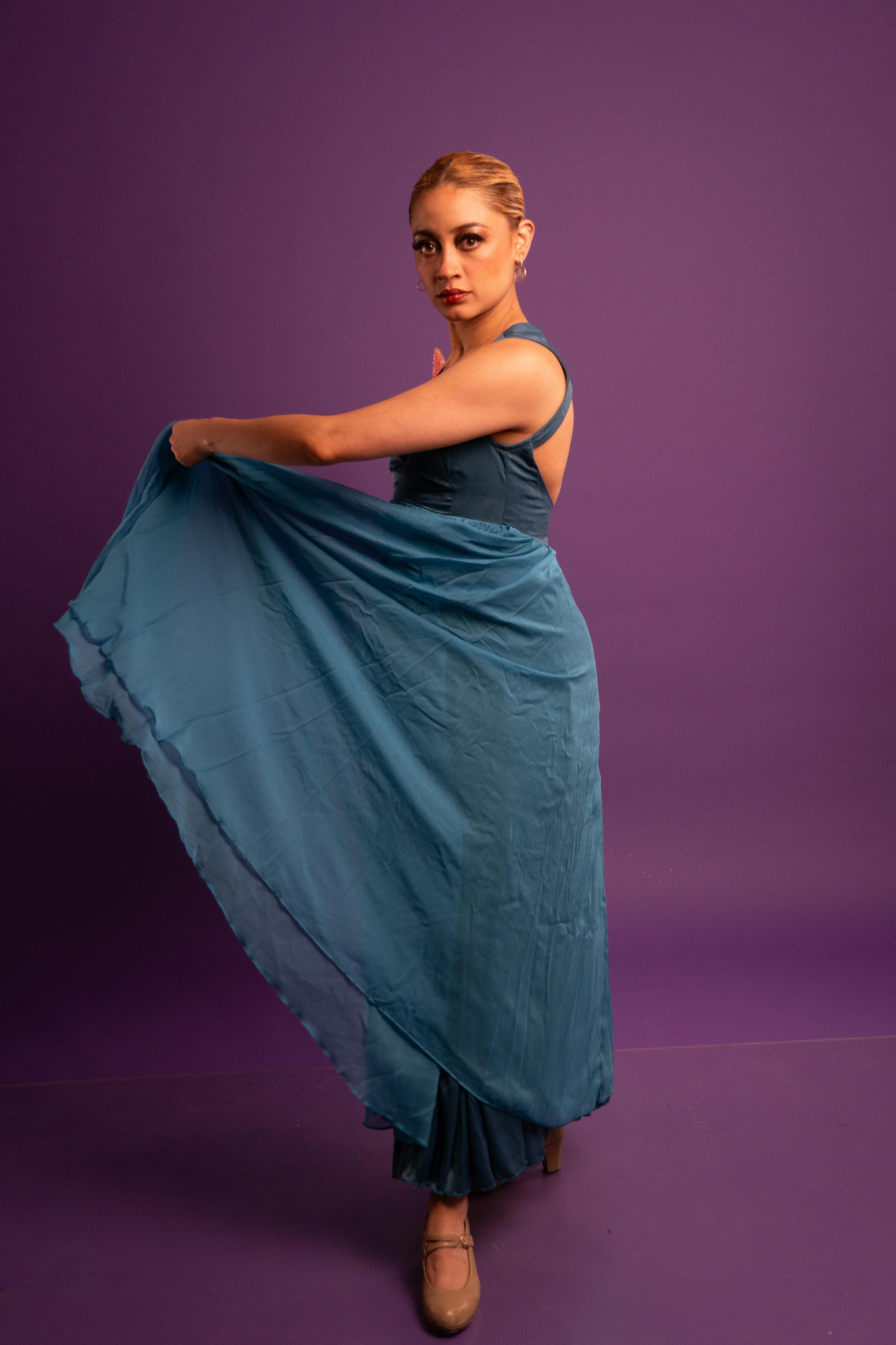 bezplatná Studiový portrét půvabné modelky tančící v modrozelených šatech flamenca na fialovém pozadí. Základová fotografie