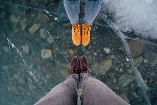 在瑞士萨赫塞尔恩，两个人站在结冰的湖面上展示他们的冬季靴子和牛仔裤