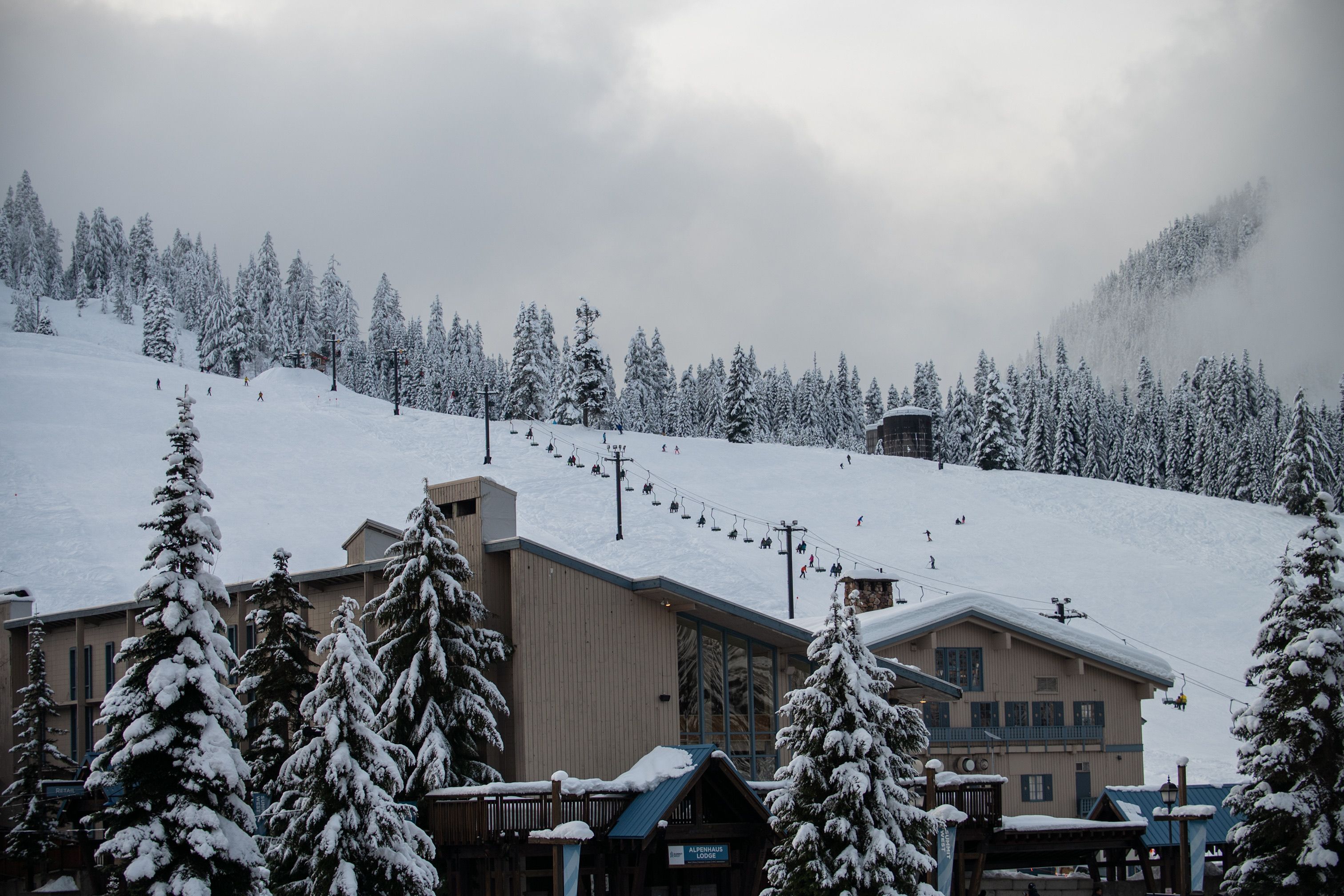 Scenic view of a snow-covered ski resort with skiers on the slope at Snoqualmie Pass.