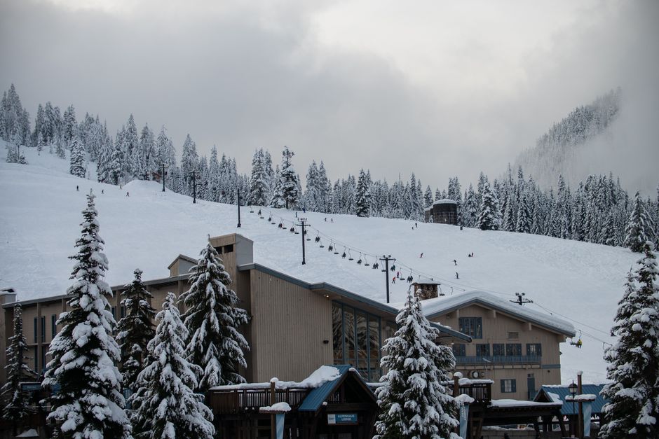 Scenic view of a snow-covered ski resort with skiers on the slope at Snoqualmie Pass.