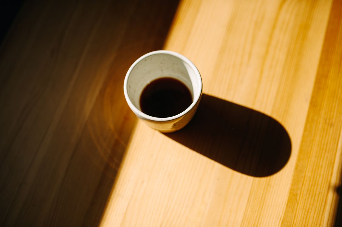 A single cup on a wooden table in warm morning light.