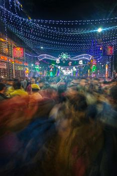 Blurred vibrant street festival in Kolkata, India at night with city lights.