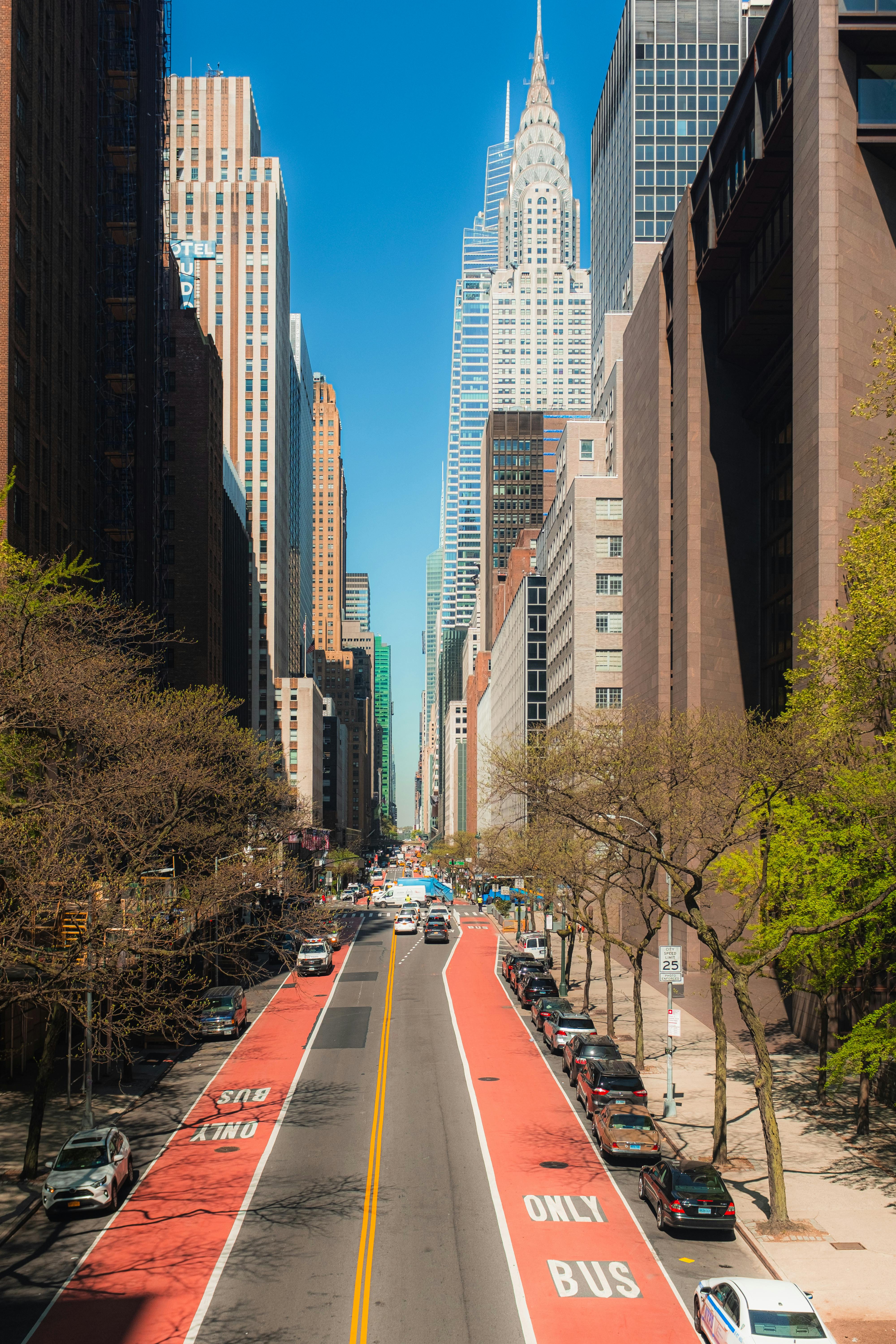 A bustling New York City street with a view of the Chrysler Building and vibrant red bus lanes.