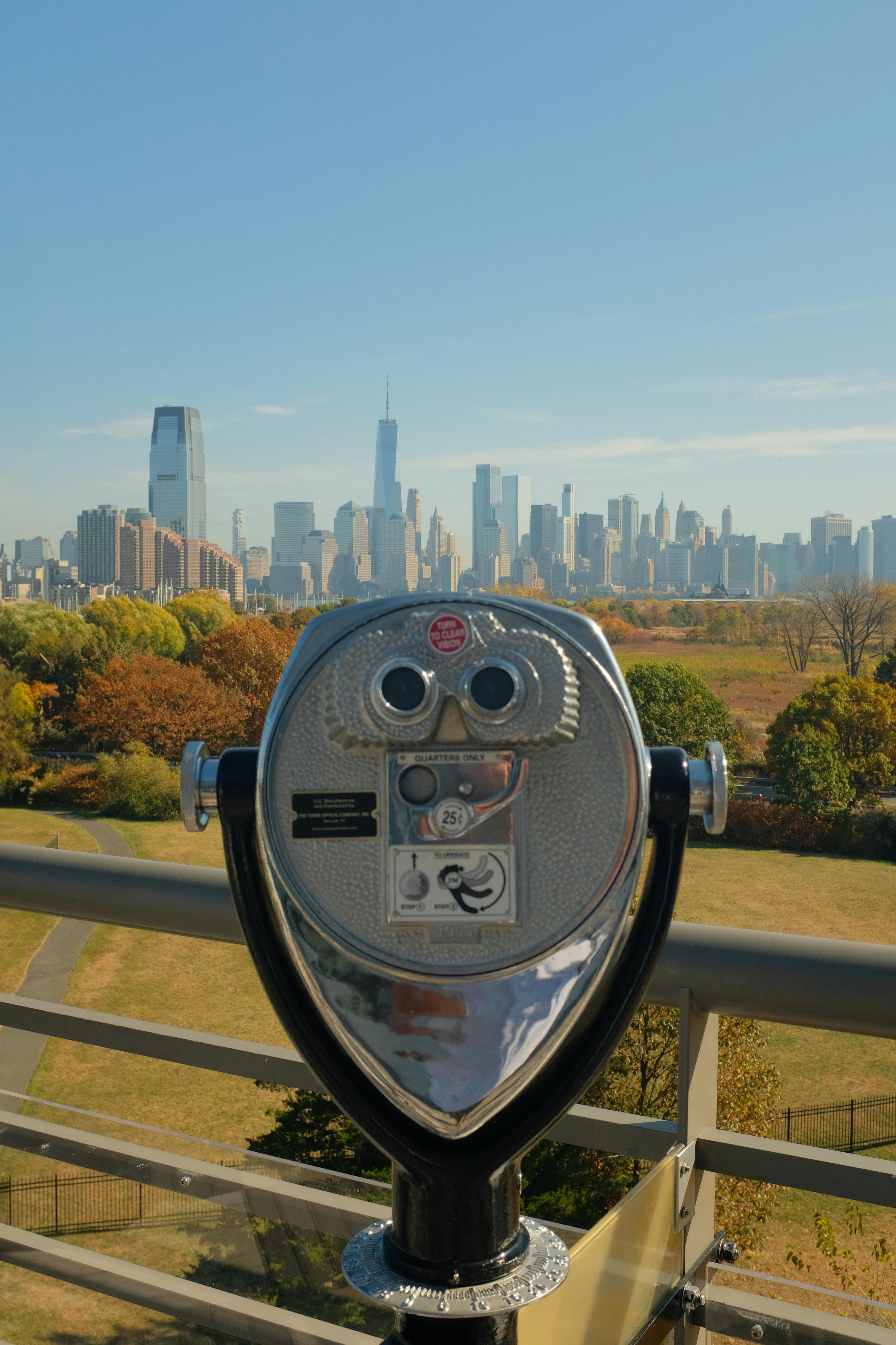 A clear day overlooking New York City skyline with foreground binoculars.