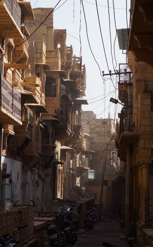Free Explore the narrow, sunlit streets of Jaisalmer with historic architecture and vibrant life. Stock Photo