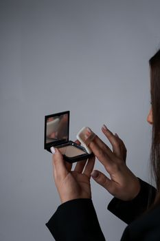 Close-up of woman's hand holding a compact mirror with puff.