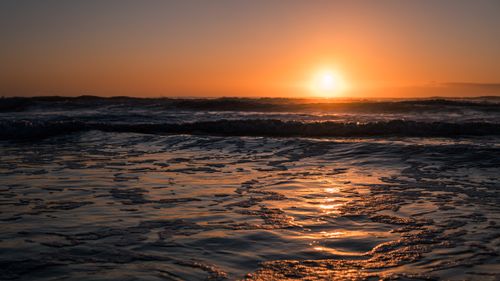 Free Stunning sunset over a calm ocean with golden reflections on water. Peaceful beach scene. Stock Photo
