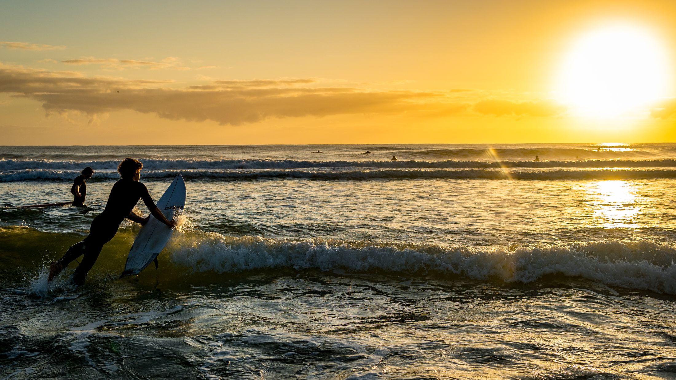 Surfistas no oceano durante a luz dourada do nascer do sol