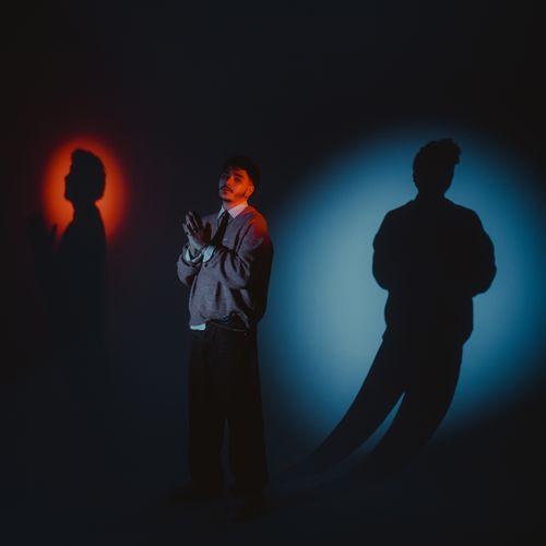 Free A person stands with dramatic shadow and colorful lighting effects in a studio setting. Stock Photo