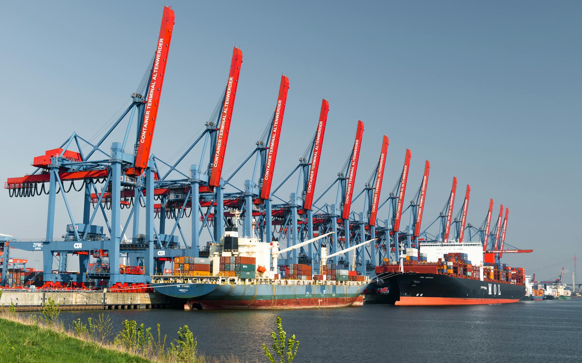Container ships docked at Hamburg Container Terminal under clear skies, showcasing global trade.