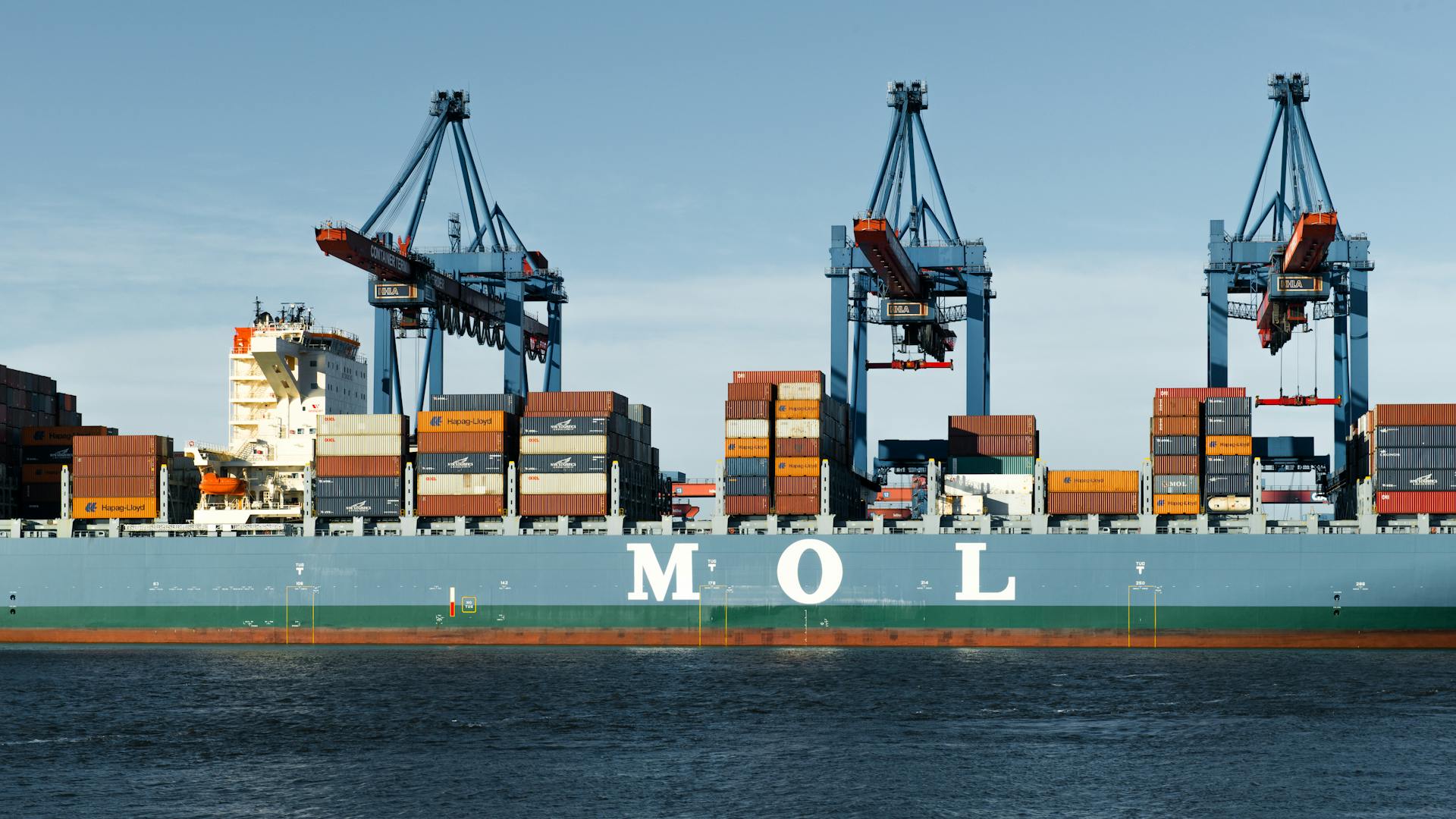 Large container ship moored at Hamburg port terminal with cranes.