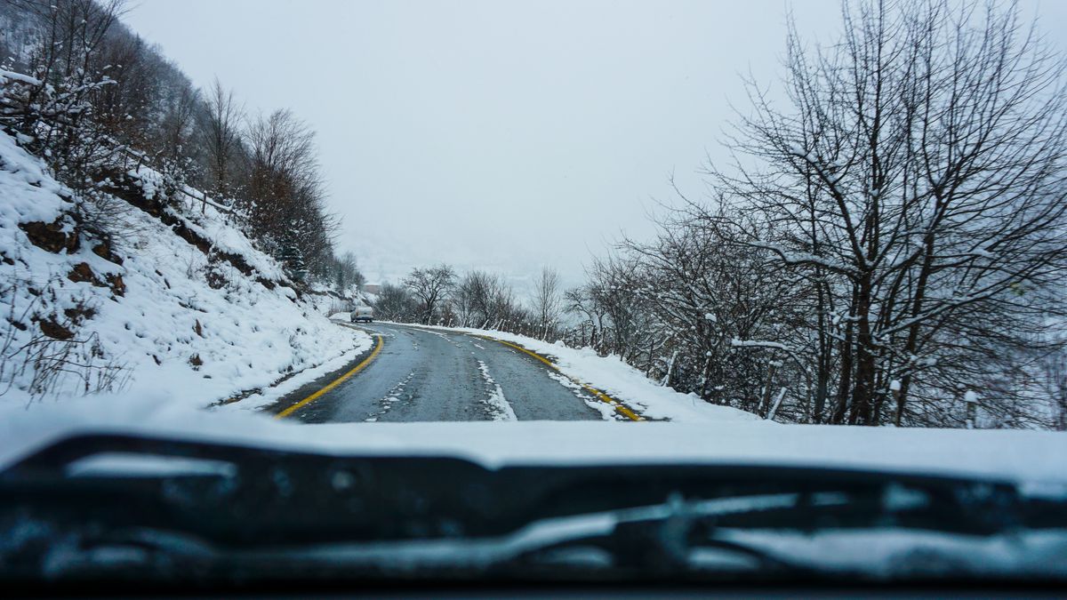 Scenic winter road winding through snow-covered trees and hills
