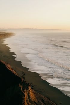 A tranquil beach view with waves and golden sunset lighting.