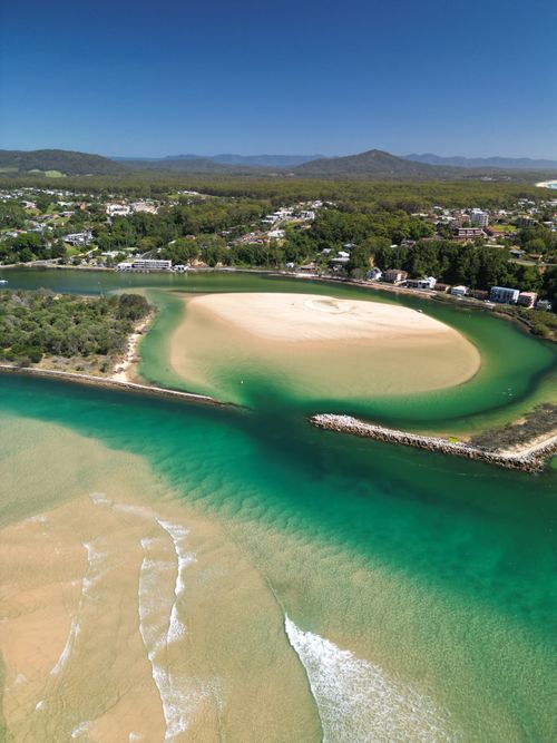 Free A stunning aerial view of a coastal inlet with turquoise waters and sandy beaches surrounded by greenery. Stock Photo
