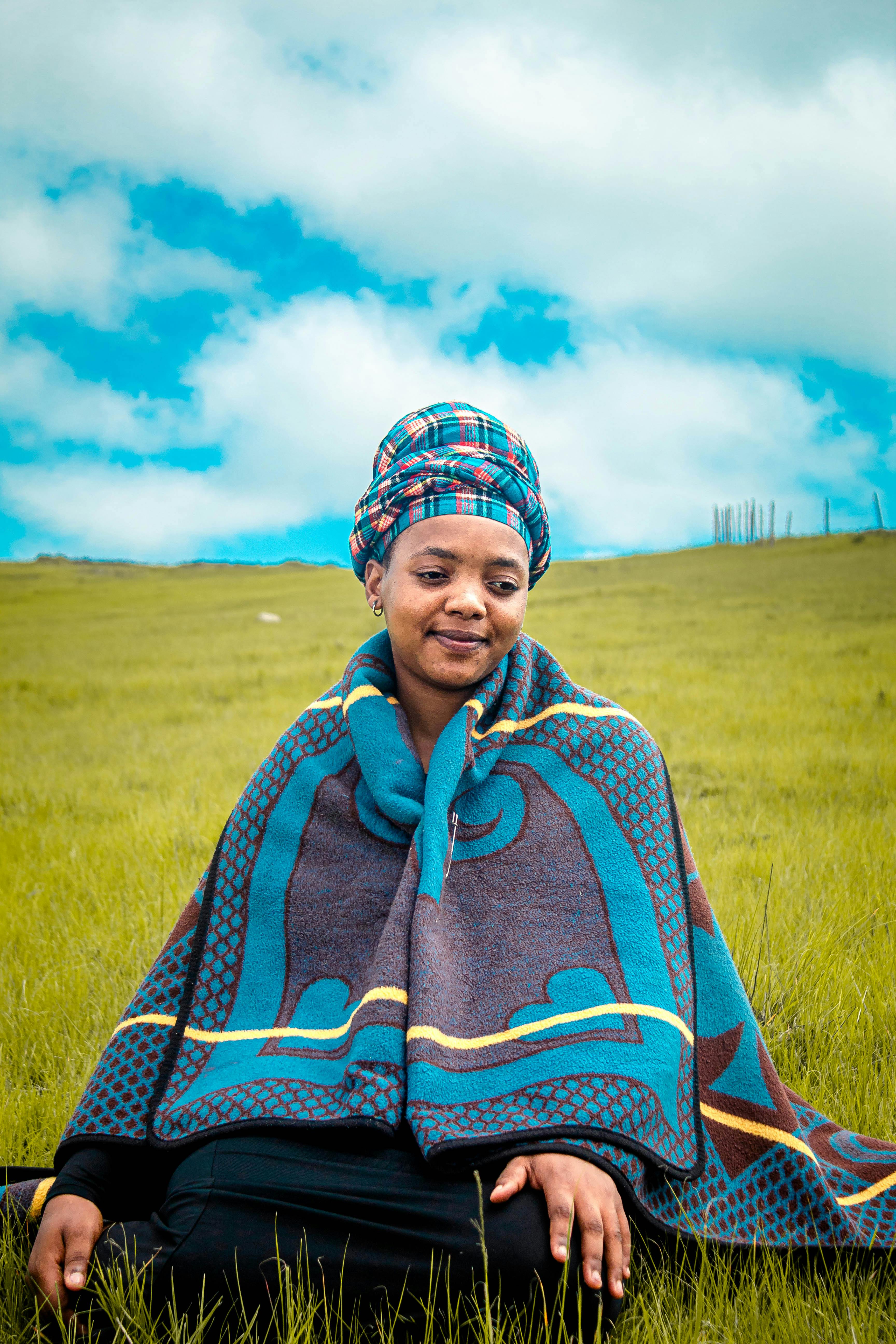 A serene portrait of a woman in traditional clothing set against the picturesque landscape of Mbizana, South Africa.
