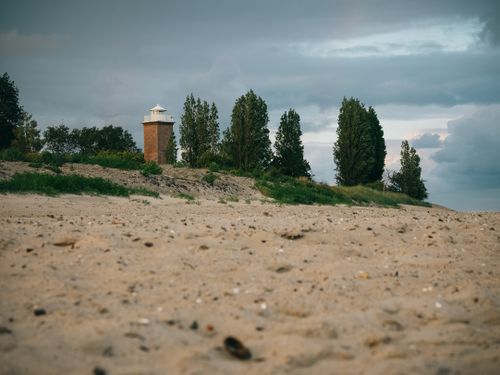 Free A serene beach with a lighthouse and trees on the coast of Neustadt in Holstein, Germany. Stock Photo
