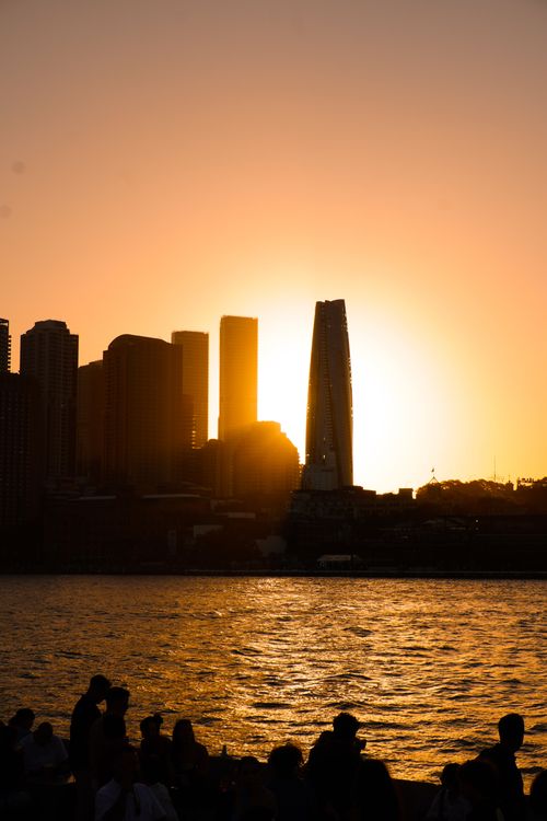 Free Dramatic city skyline silhouette against a vibrant sunset, with shimmering waterfront. Stock Photo