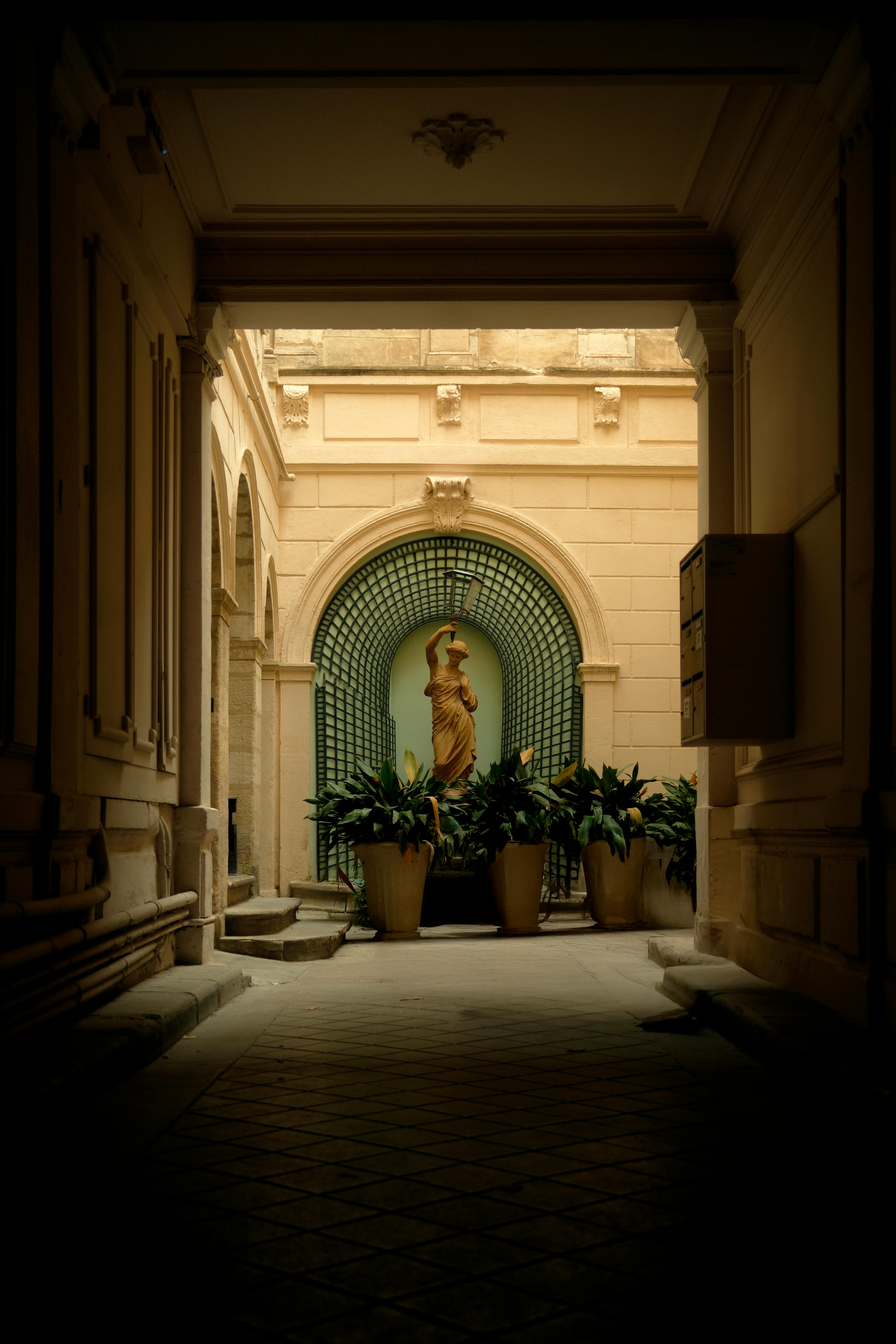 A serene stone statue surrounded by plants in a classic courtyard setting.