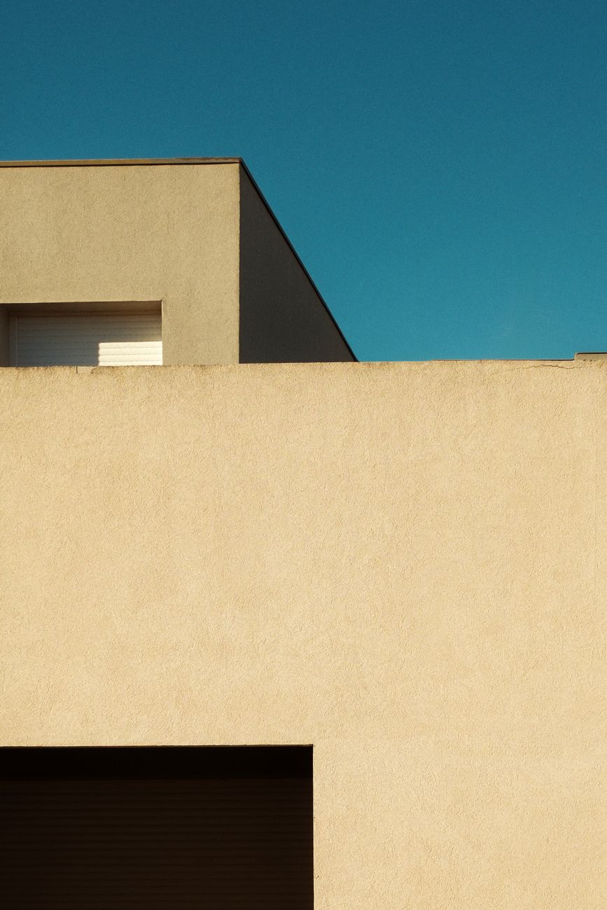 Elegant minimalist architecture under a clear blue sky, showcasing modern design and clean lines.