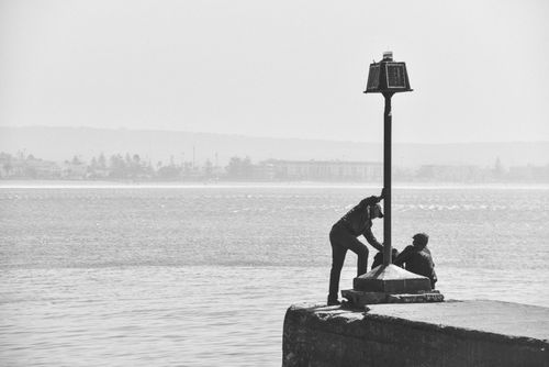 Free Silhouetted figures on a pier by calm waters, creating a serene and contemplative scene. Stock Photo