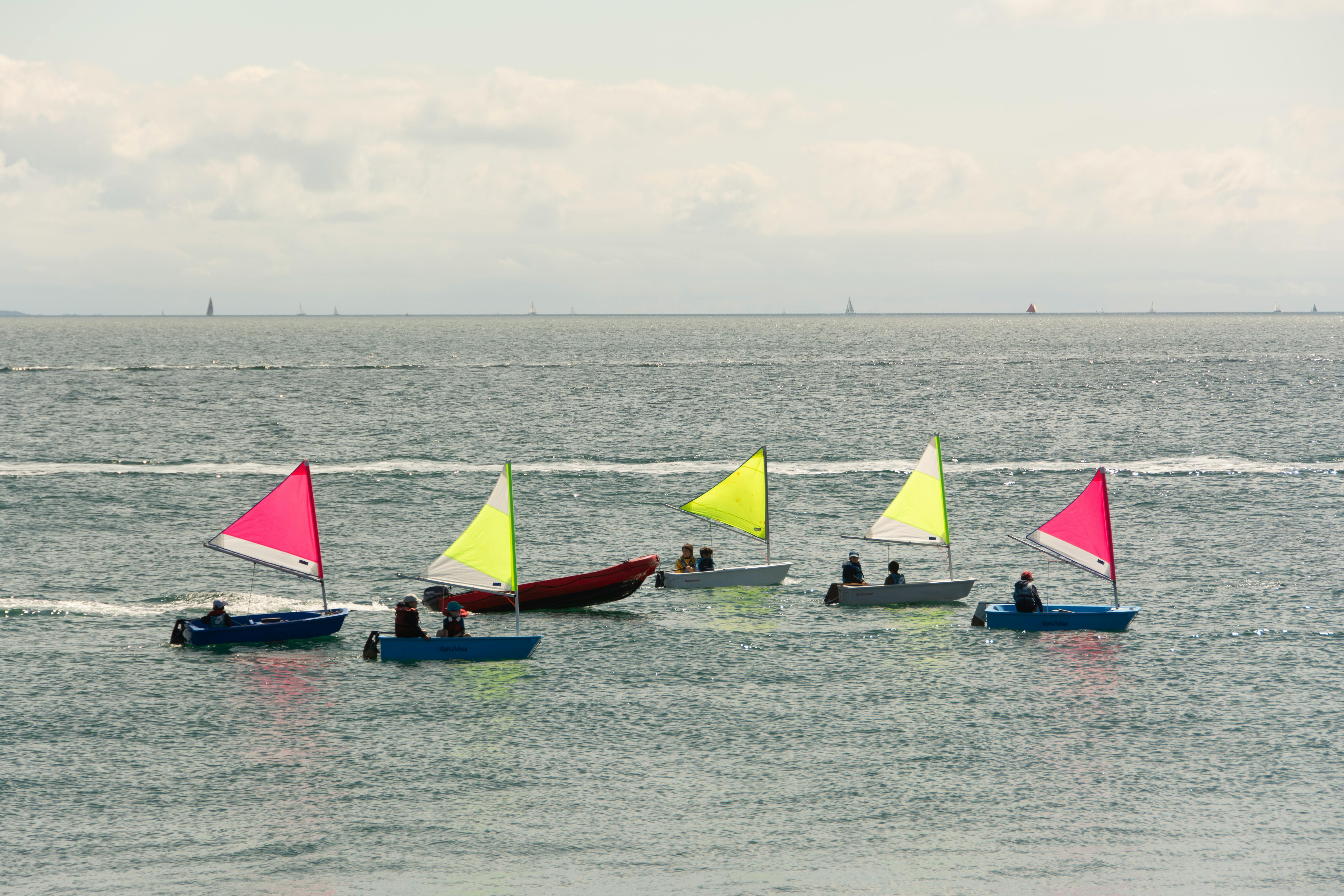 Children learning to sail in colorful boats on the calm sea in Quiberon.