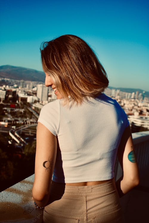 Back View Photo of Smiling Woman in White Crop Top T-shirt and Brown Pants
