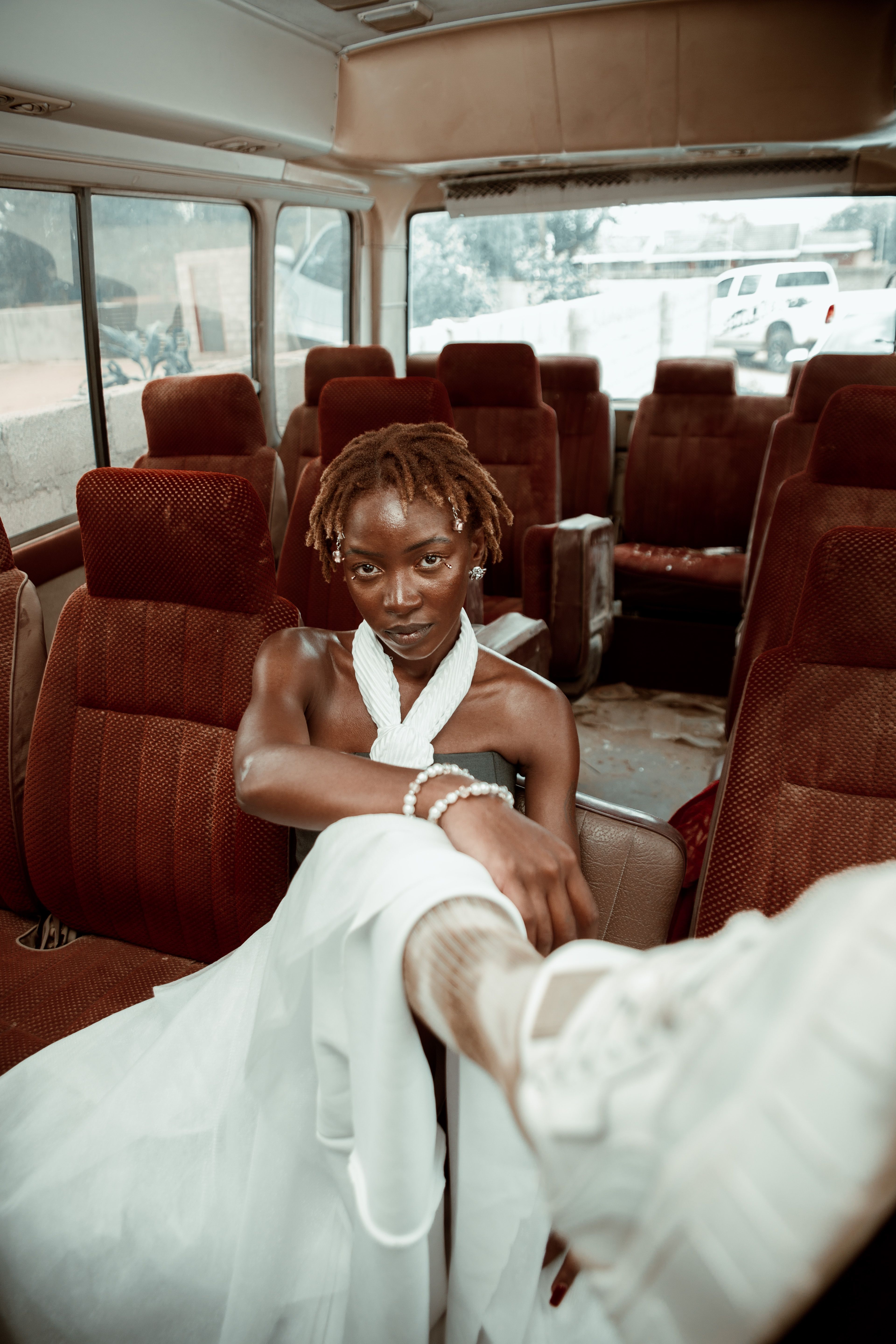Stylish young adult seated confidently in vintage bus interior, showcasing unique fashion and attitude.