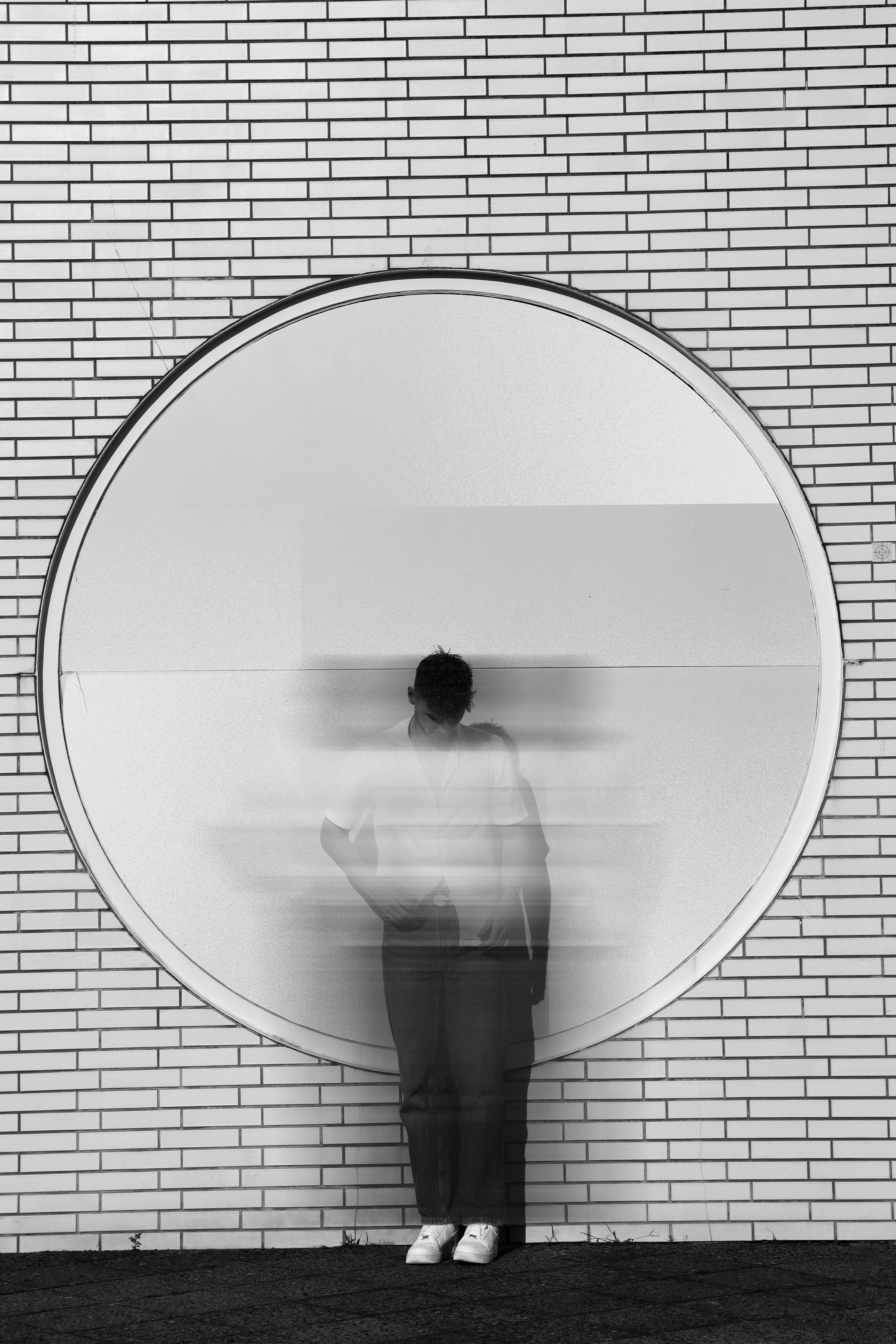 A blurred silhouette within a circular frame on a brick wall in Berlin.