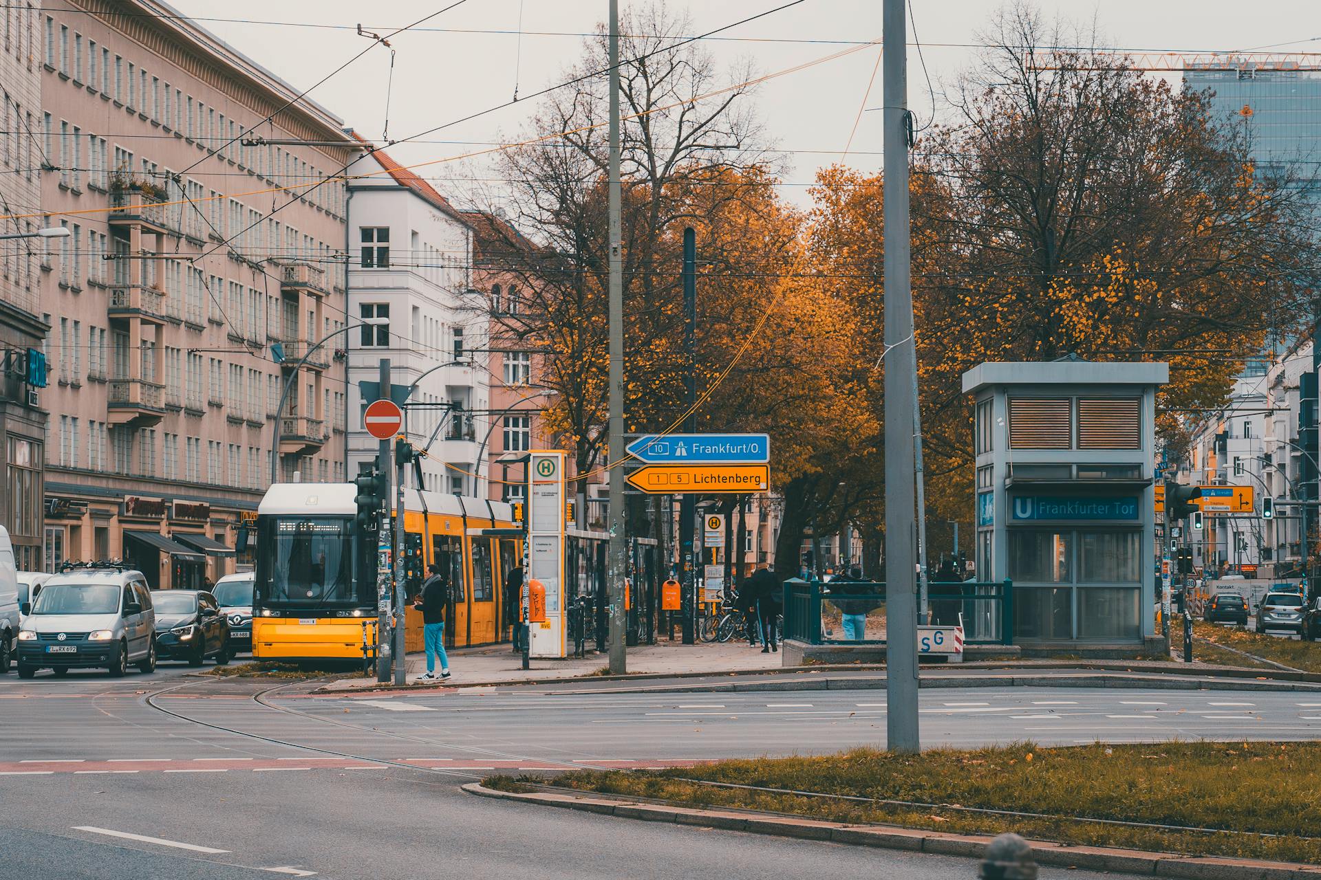 A vibrant cityscape in Berlin showcasing a tram amid fall foliage, capturing everyday life.